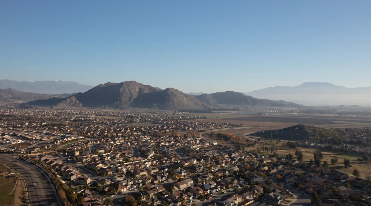 Aerial view of houses California real estate with roads, valleys, and mountains.