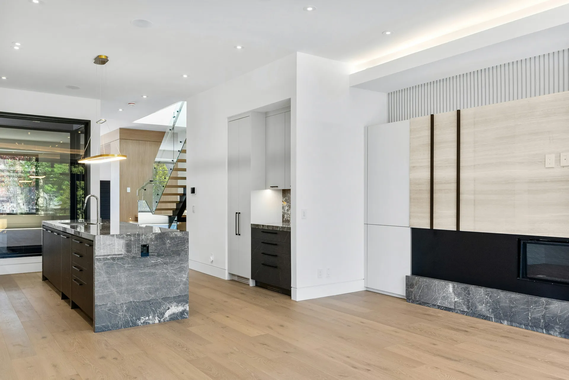Kitchen with island, dark cabinets, stone counters, big windows, and wood floor.