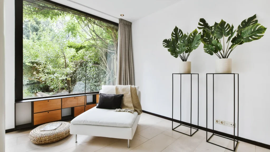 Living room with white lounger, big window, and plants.