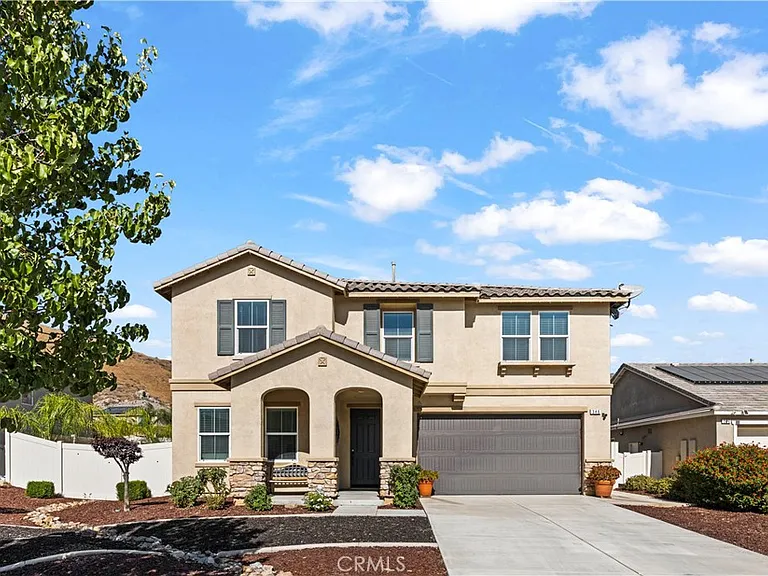 Two story house California real estate with tiled roof, front porch, double garage, and garden.